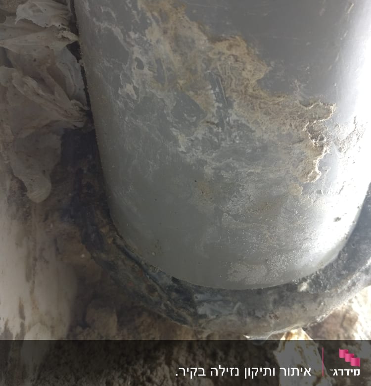 צינור אפור עם לכלוך וחול סביבו